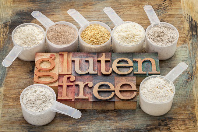 measuring scoops of gluten free flours (almond, coconut, teff, flaxseed meal, whole rice, brown rice, buckwheat) wit a text in letterpress wood type